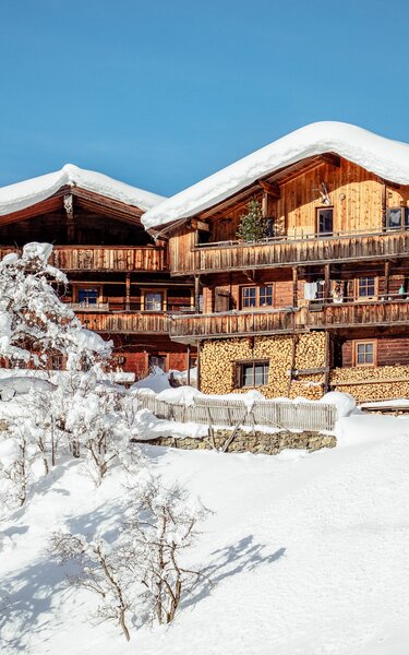 Zwei Häuser im typisch Alpbachtaler Baustil, umgeben von schöner, verschneiter Winterlandschaft 