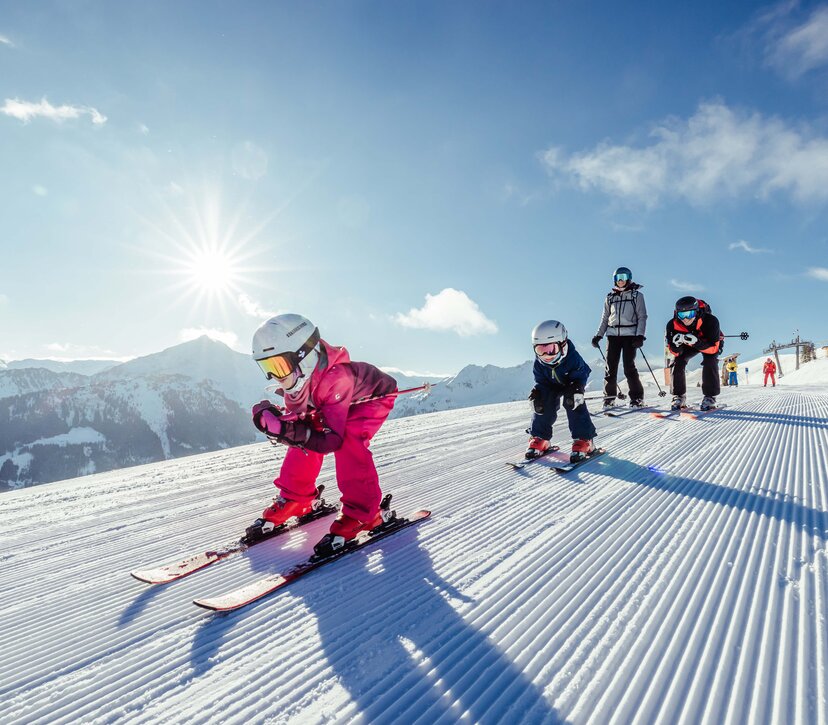 eine Familie fährt gemeinsam der Skipiste in Alpbach entlang, die Kinder fahren vor, die Eltern hinten nach  | © Alpbachtal Tourismus | shootandstyle 