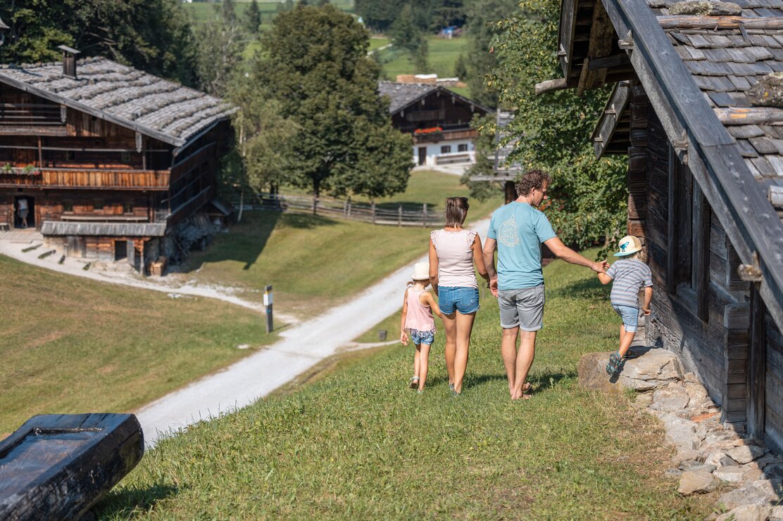 Eine Familie spaziert gemütlich durch das Museum Tiroler Bauernhöfe und betrachtet dabei die alten Bauernhäuser  | © Alpbachtal Tourismus | shootandstyle 