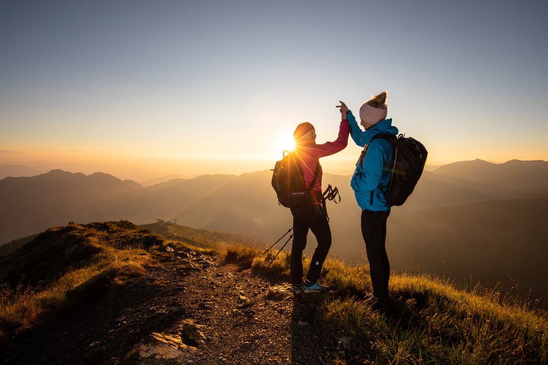 Zwei Freundinnen klatschen vor Freude in die Hände und freuen sich über den schönen Sonnenaufgang  | © Alpbachtal Tourismus | shootandstyle 