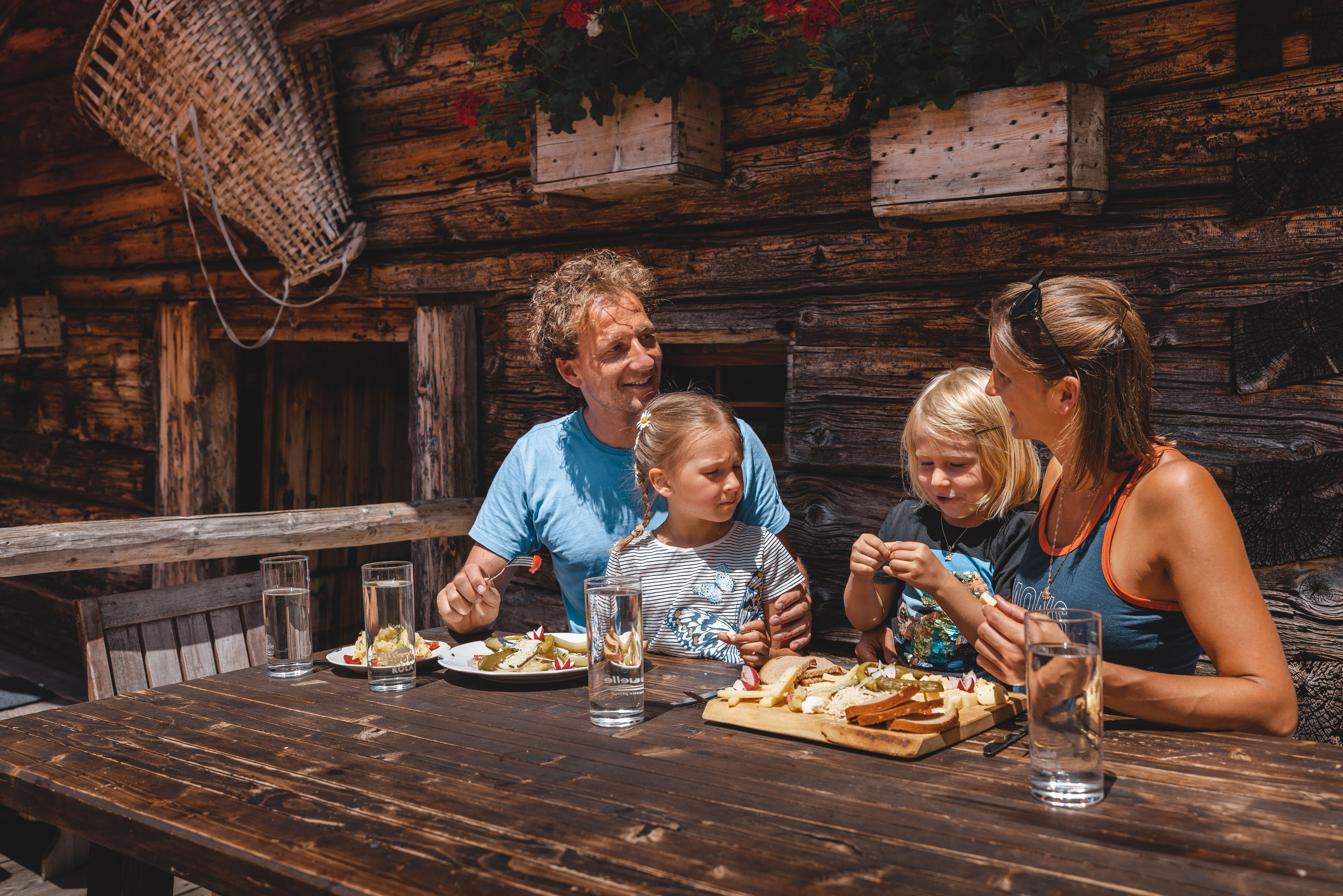 Eine Familie isst genüsslich eine Brettljause auf der Farmkehralm in Inneralpbach | © Alpbachtal Tourismus | Mathäus Gartner 