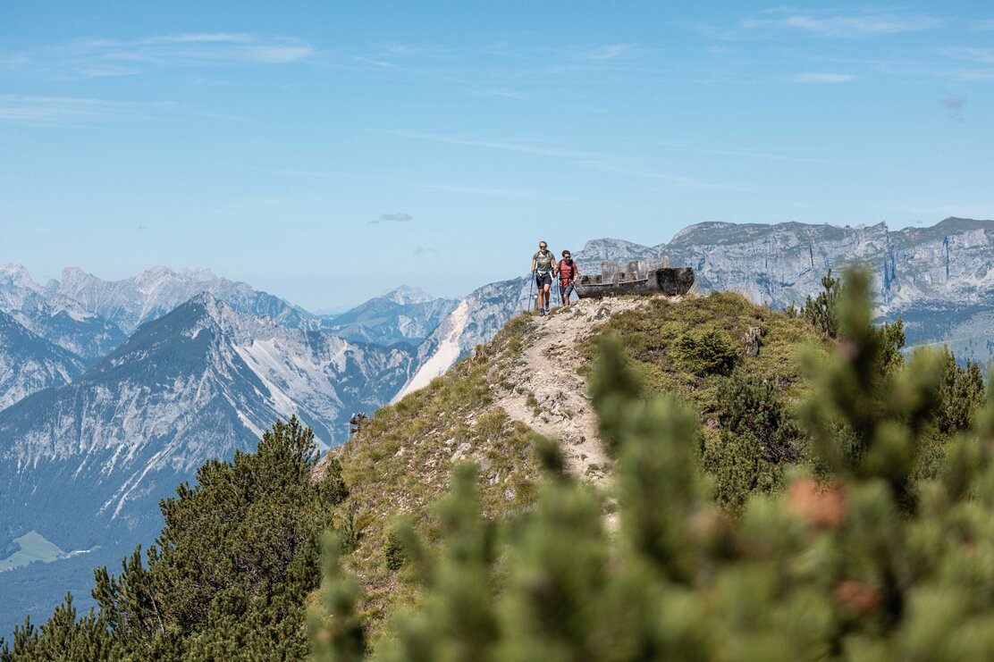 Ein Paar wandert gemeinsam an einer Rastbank am Berg Gratlspitze vorbei  | © Alpbachtal Tourismus | shootandstyle