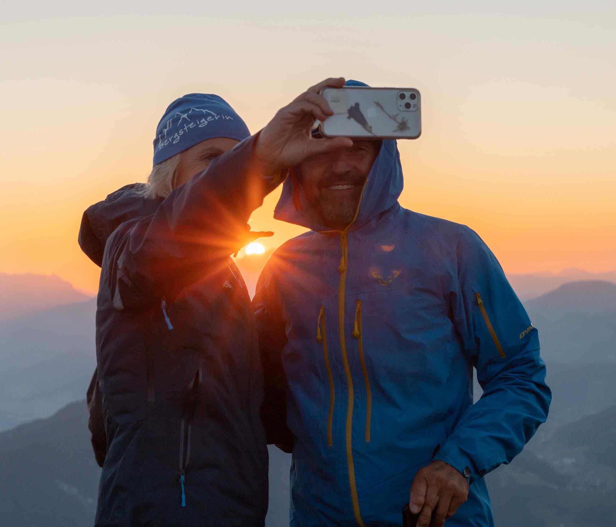 Auf diesem Bild sieht man eine Frau und einen Mann, welche ein Selfie machen, im Hintergrund der schöne Sonnenaufgang  | © Alpbachtal Tourismus | shootandstyle 